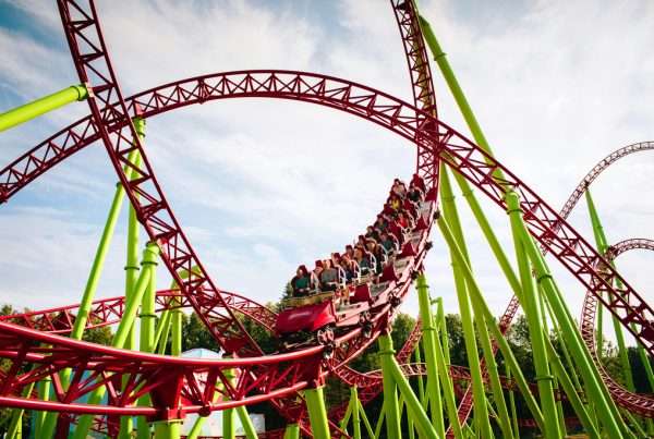 Rollercoaster large loops in an amusement park. The cabin with cheerful people laughs furiously and screams while riding an amusement ride. Summer panorama. Background.